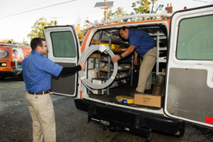 Electricians unloading wiring equipment from a service van